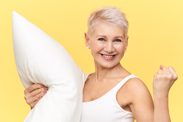 isolated-shot-joyful-excited-mature-european-female-clenching-fist-carrying-white-feather-pillow-feeling-full-energy-as-she-got-enough-sleep-looking-camera-with-radiant-vivacious-smile_343059-1996